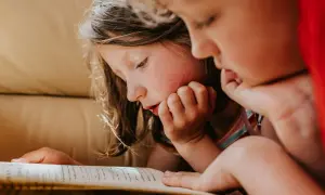 Dos niños concentrados en la lectura de un libro, ideal para lectura para niños de 10 a 12 años.
