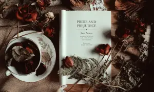 Un libro abierto de "Orgullo y Prejuicio" de Jane Austen, rodeado de rosas secas y helechos, evoca la atmósfera de sus obras.