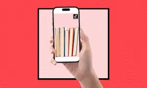 Una mano sostiene un teléfono con libros en la pantalla, mostrando la comunidad de **que es booktok** y sus recomendaciones literarias.