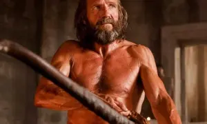 Homero, con su mirada intensa y barba, empuña un arco. Sus frases resuenan en la historia.