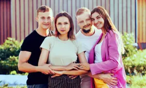 Dos parejas sonríen, unidas en un abrazo que ilustra el poliamor que es, una conexión amorosa y respetuosa entre varias personas.
