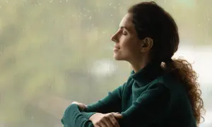 Mujer con los ojos cerrados, disfrutando de la lluvia y la paz interior.