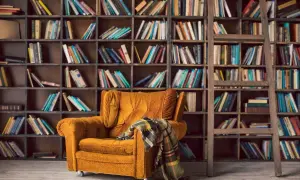 Un sillón acogedor y una manta a cuadros esperan en este rincón perfecto para un club del libro. Estanterías llenas de libros invitan a la lectura.