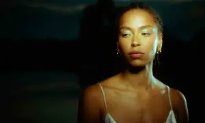 Mujer con mirada perdida, reflejando una posible depresión reactiva. La luz resalta su rostro y hombros.