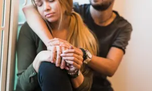 Una pareja se abraza, ella con los ojos cerrados y él consolándola, transmitiendo un profundo miedo al abandono.
