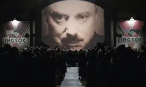 Multitud ante pantalla gigante con el rostro de un hombre y el logo de INGSOC. Un eco de las **1984 frases** que controlan sus mentes.