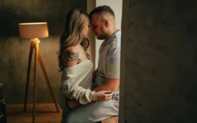 Una pareja se abraza tiernamente, sus frentes juntas. Ella tiene un tatuaje de flor en el hombro. Esto es hacer el amor de verdad: conexión y ternura.