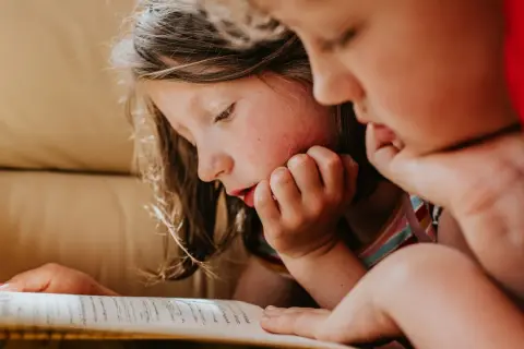 Dos niños concentrados en la lectura de un libro, ideal para lectura para niños de 10 a 12 años.