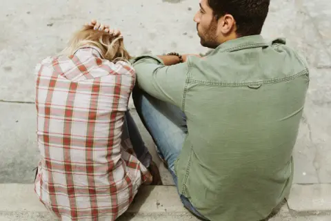 Pareja sentada, ella con la cabeza apoyada en las manos, él mirándola. Un momento íntimo, quizás el inicio de cómo liarse con alguien.