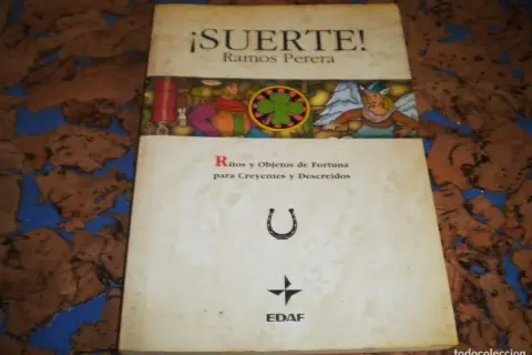 El libro de la buena suerte, "¡Suerte!" de Ramos Perera, explora ritos y objetos de fortuna. Incluye una herradura y un trébol.