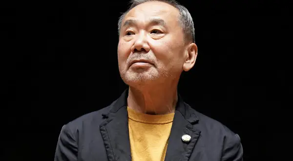 Haruki Murakami, autor de frases memorables, mira hacia arriba con una expresión pensativa.