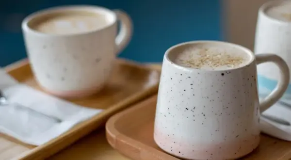 Dos tazas de café con leche espumosa, un recordatorio de los beneficios de dejar el café.