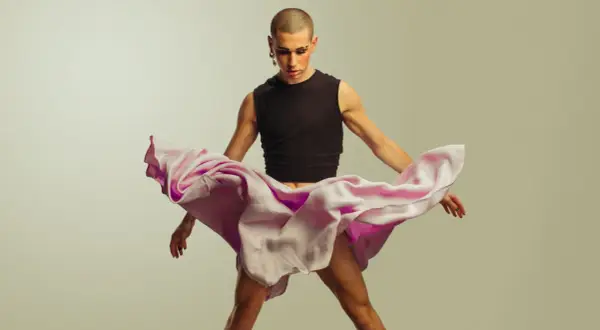 Joven con maquillaje y falda rosa ondeante, desafiando la masculinidad frágil.
