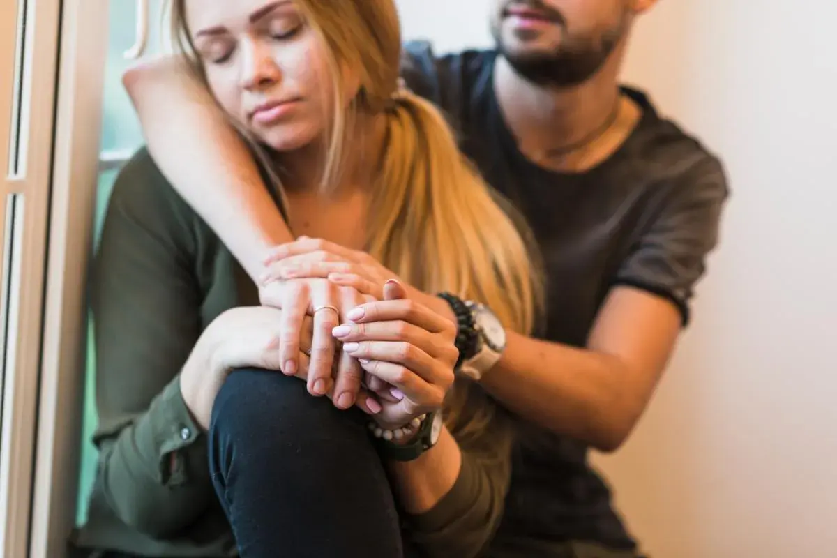 Una pareja se abraza, ella con los ojos cerrados y él consolándola, transmitiendo un profundo miedo al abandono.