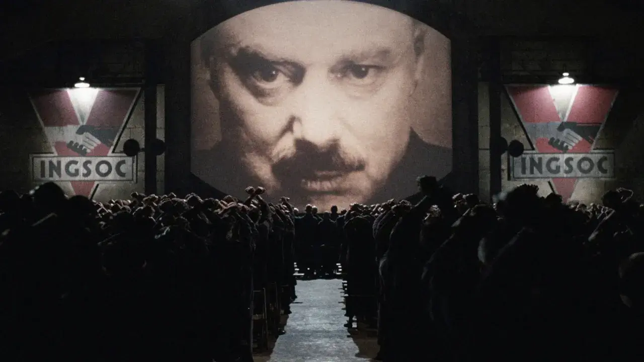 Multitud ante pantalla gigante con el rostro de un hombre y el logo de INGSOC. Un eco de las **1984 frases** que controlan sus mentes.