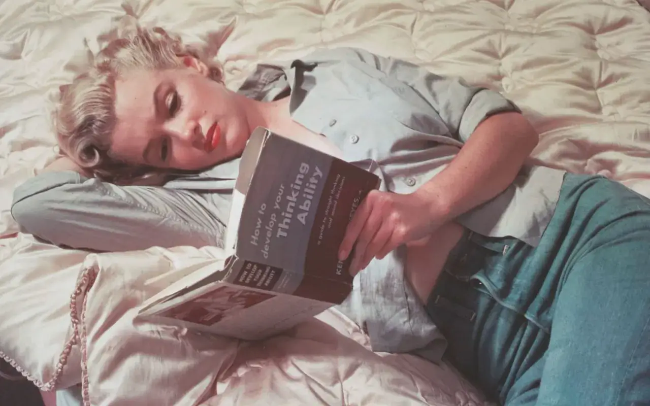 Marilyn Monroe lee un libro sobre c&oacute;mo desarrollar la habilidad de pensar, un ejemplo de sabias frases de mujeres fuertes que buscan el conocimiento.