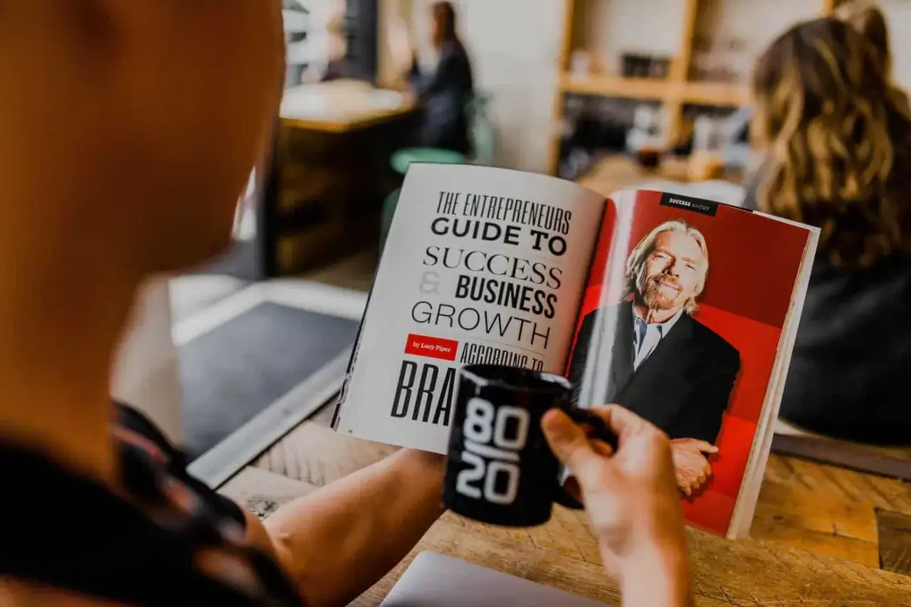 Persona lee un libro sobre &eacute;xito empresarial, con Richard Branson en la portada. Insp&iacute;rate como el vendedor m&aacute;s grande del mundo.