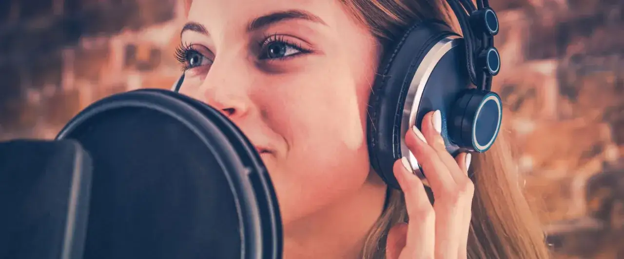 Una joven con auriculares graba su voz para un audiolibro.