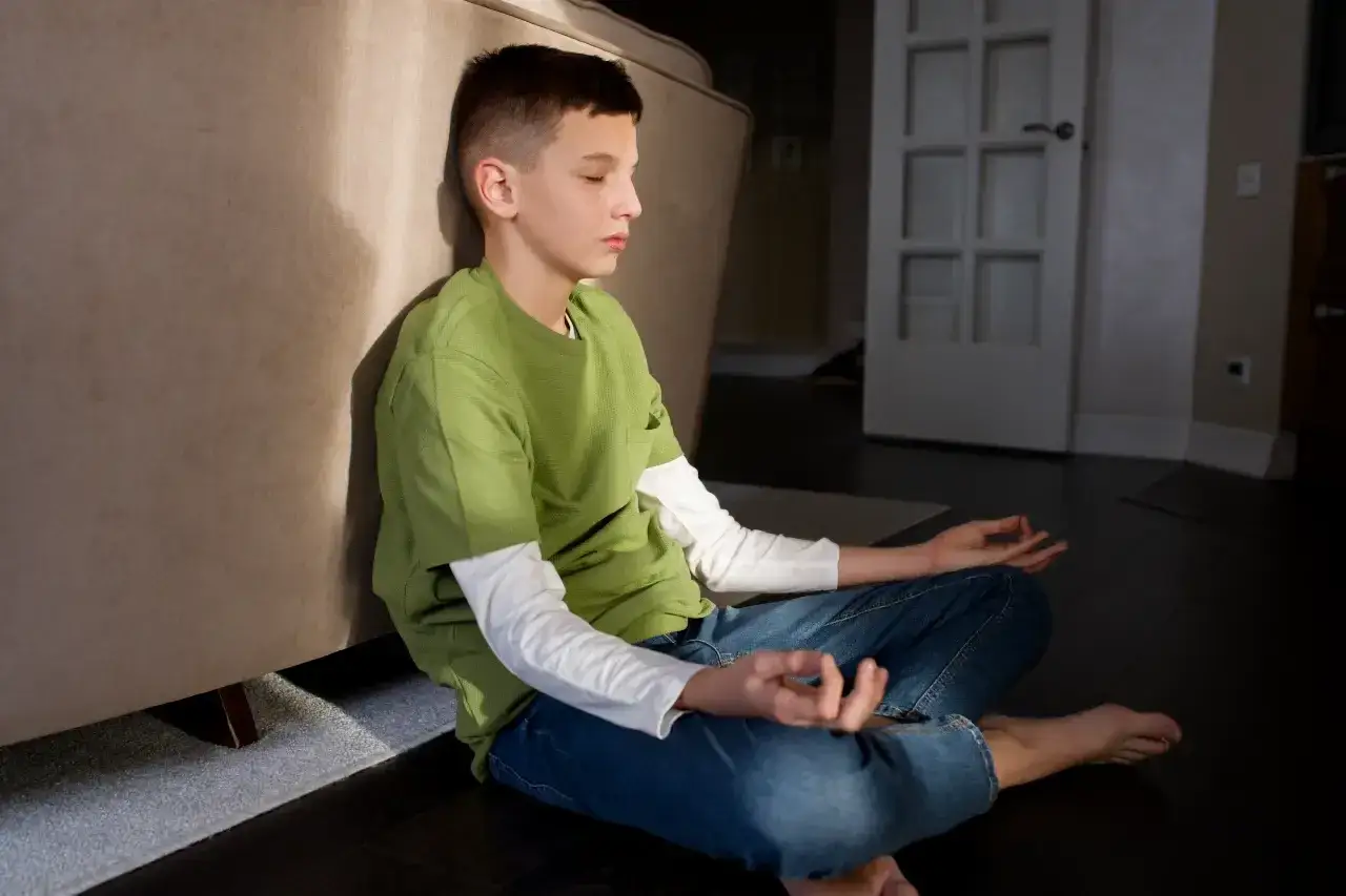 Joven meditando, practicando el control emocional. Sentado en el suelo, con los ojos cerrados y las manos en posición de loto.