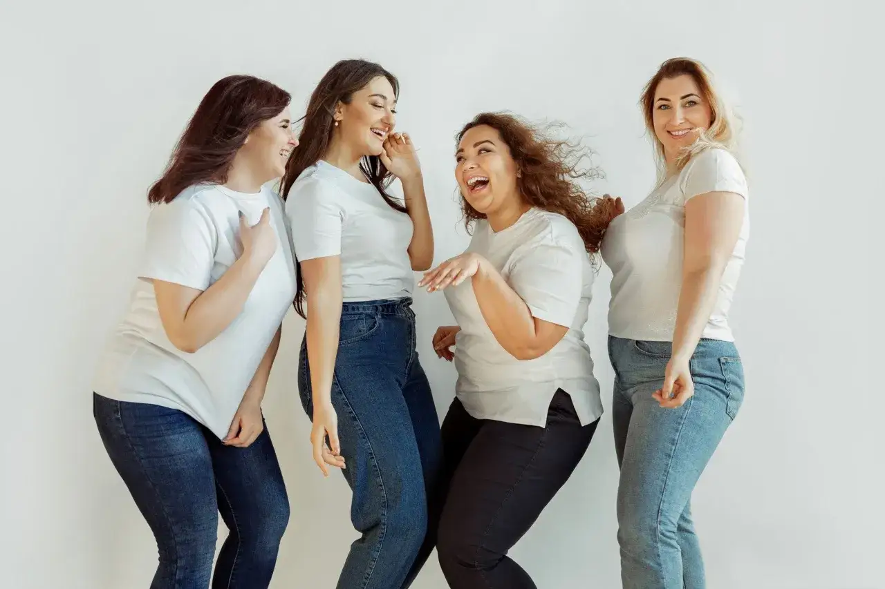 Cuatro mujeres sonriendo y riendo juntas, celebrando la belleza de todas las formas y tama&ntilde;os. Un hermoso ejemplo de body positive.