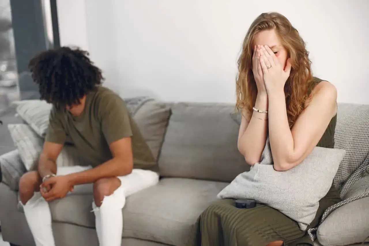 Una pareja sentada en un sof&aacute;, ella llora con las manos en la cara, &eacute;l le da la espalda. El miedo al abandono se siente en el aire.