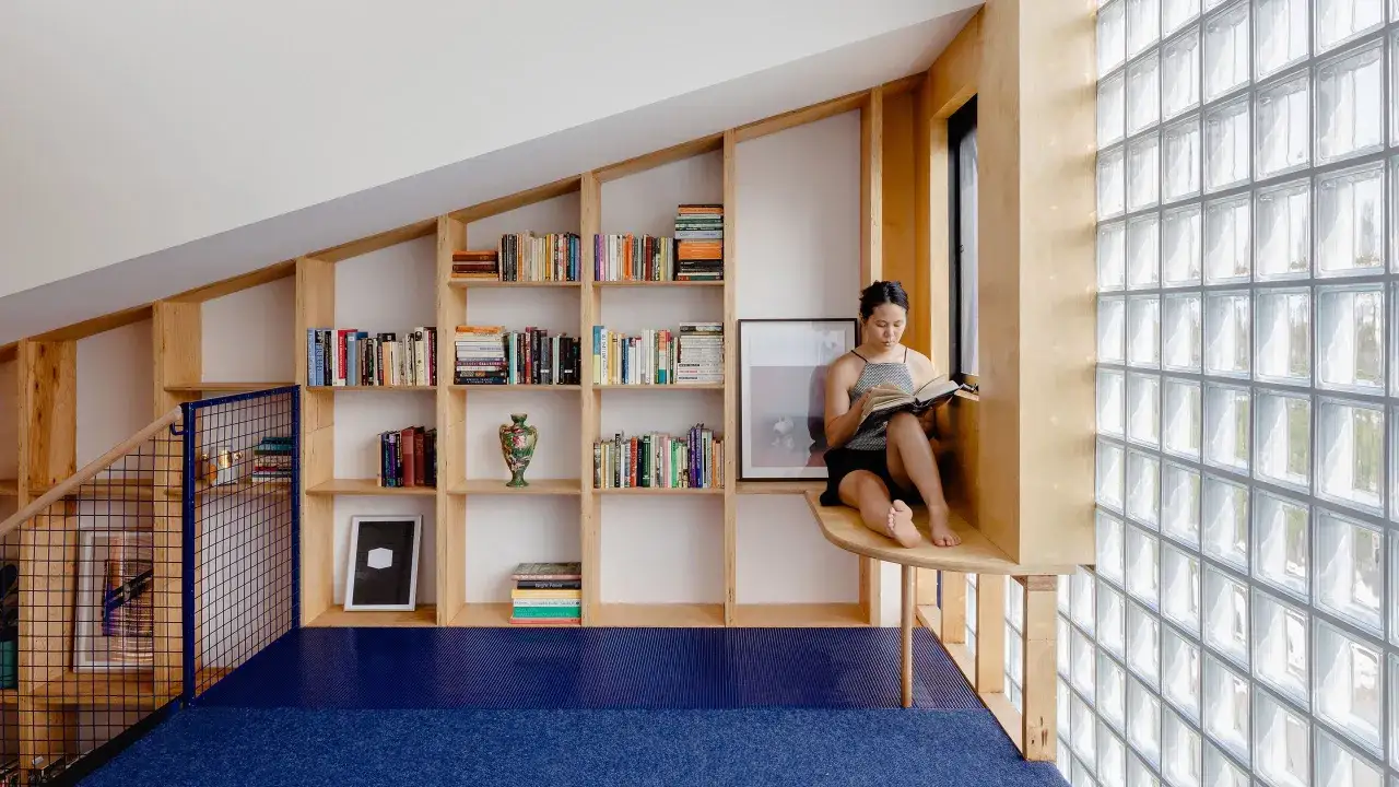 Mujer lee en un rinc&oacute;n acogedor junto a estanter&iacute;as llenas de libros que te cambian la vida.