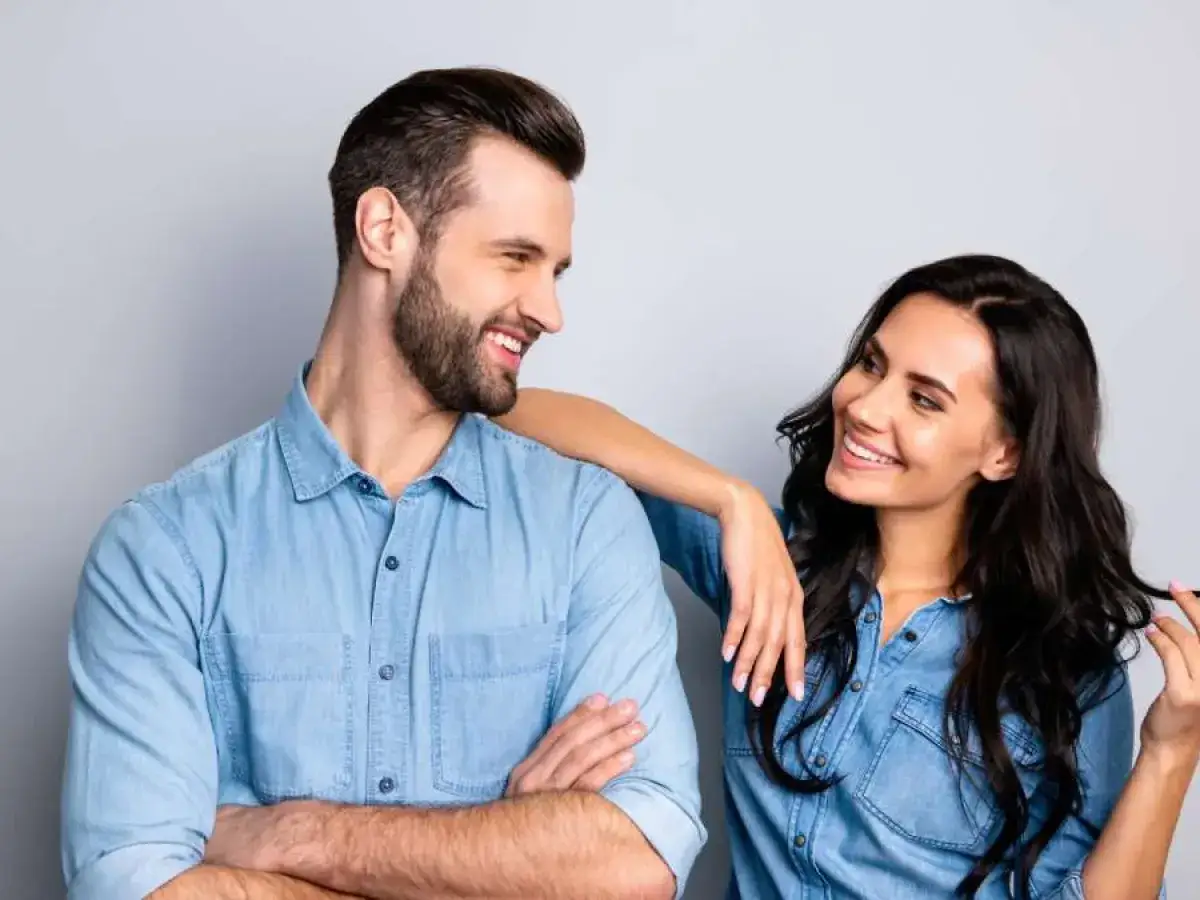 Pareja sonriente, &eacute;l con brazos cruzados, ella con mano en su hombro. &iquest;C&oacute;mo saber si le gustas a un hombre? Sus miradas lo dicen todo.