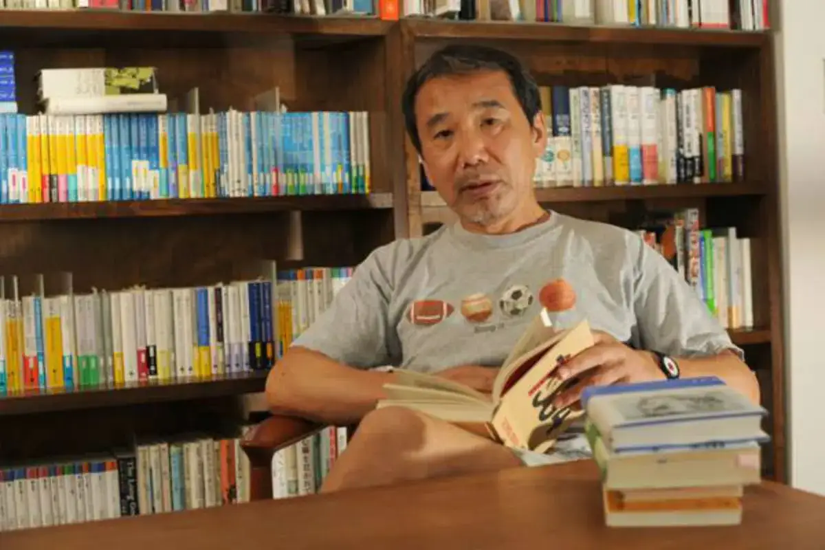 Un hombre lee rodeado de libros, quiz&aacute;s buscando inspiraci&oacute;n para sus propias haruki murakami frases.