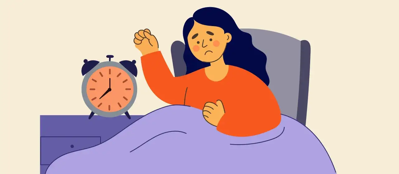 Mujer en cama con despertador, agotada. &iquest;Hipersomnia qu&eacute; es? El sue&ntilde;o excesivo puede ser un s&iacute;ntoma.