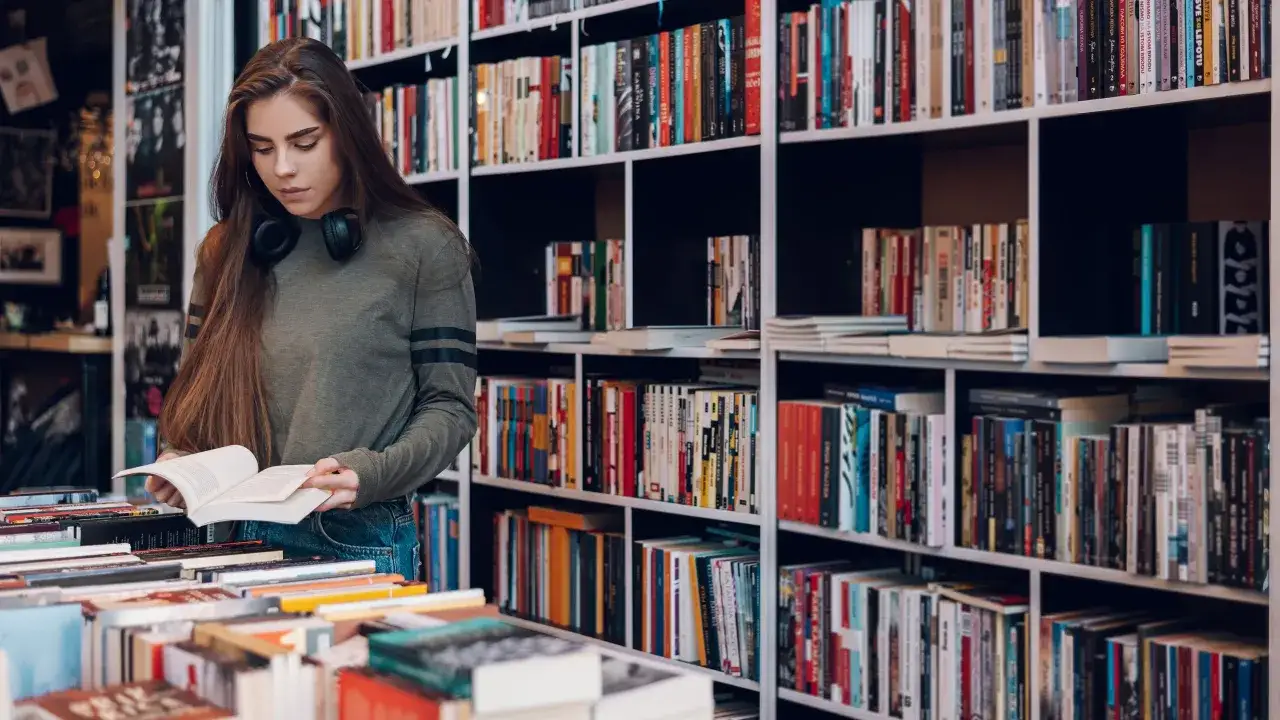 Joven buscando libros recomendados para adolescentes de 13 a&ntilde;os entre estanter&iacute;as llenas de t&iacute;tulos.