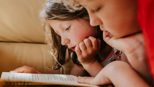 Dos niños concentrados en la lectura de un libro, ideal para lectura para niños de 10 a 12 años.