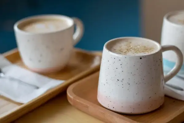 Dos tazas de café con leche espumosa, un recordatorio de los beneficios de dejar el café.