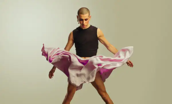 Joven con maquillaje y falda rosa ondeante, desafiando la masculinidad frágil.