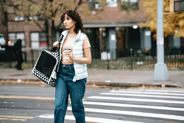 Mujer con bolso y café cruza la calle, lista para aplicar las 7 reglas para adelgazar caminando.