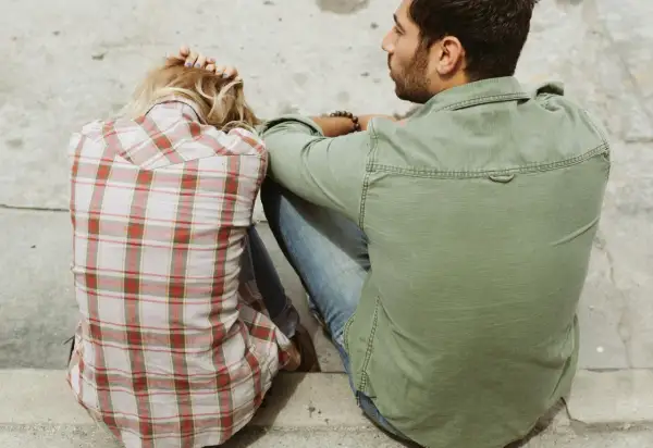Pareja sentada, ella con la cabeza apoyada en las manos, él mirándola. Un momento íntimo, quizás el inicio de cómo liarse con alguien.